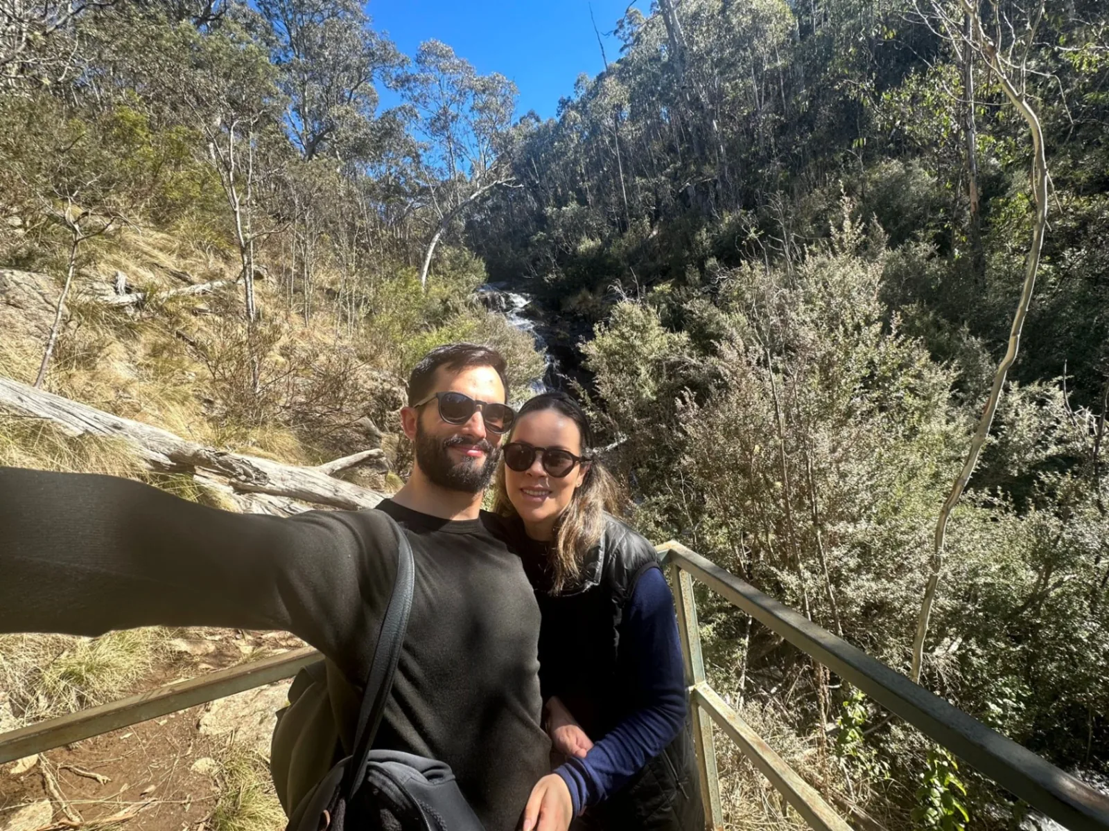 Carolina y Nacho caminando junto a una cascada en el bosque australiano